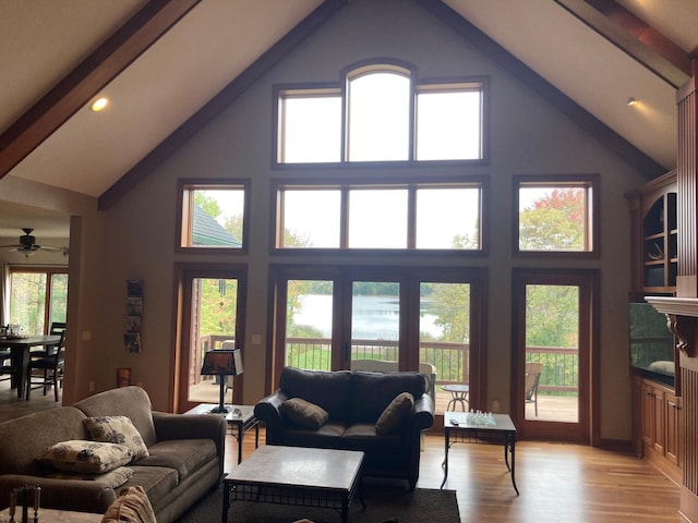 living room with light wood finished floors, beamed ceiling, and a towering ceiling