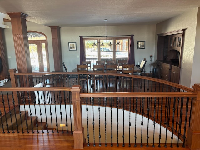 bar featuring ornate columns, wood finished floors, a textured ceiling, and an inviting chandelier