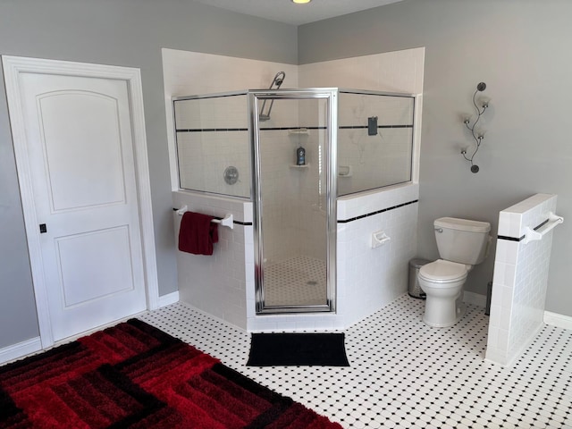 bathroom featuring a stall shower, baseboards, tile patterned flooring, and toilet