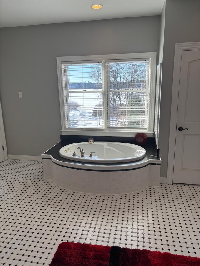 full bathroom featuring a bath and baseboards