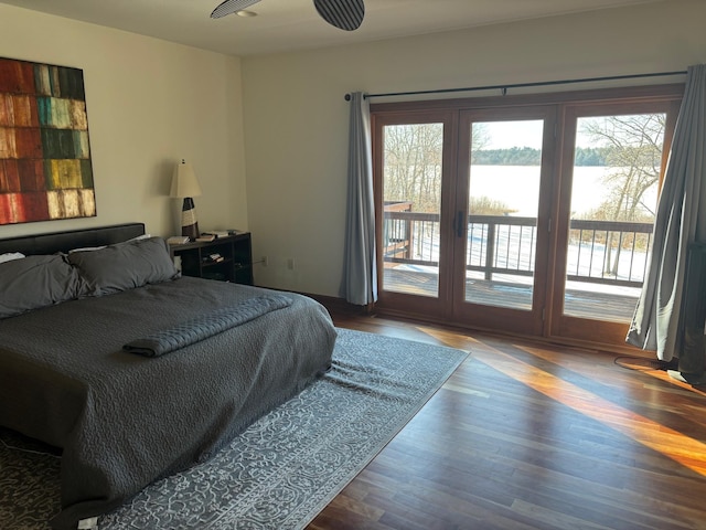 bedroom with a water view, access to exterior, and wood finished floors