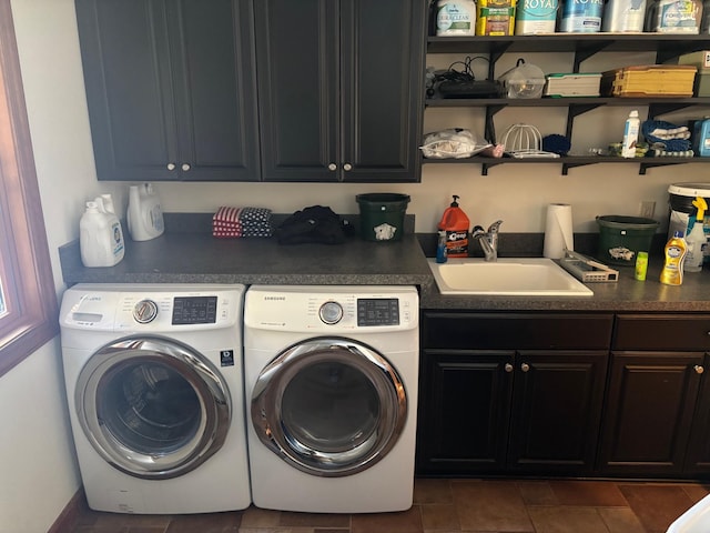 laundry area with washer and dryer, cabinet space, a sink, and dark tile patterned flooring