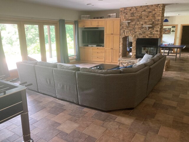 living area with stone finish flooring, a healthy amount of sunlight, and a stone fireplace