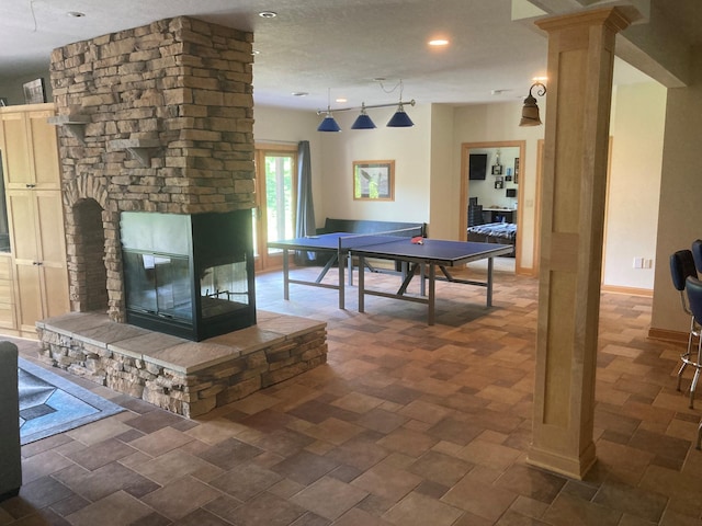 recreation room with ornate columns, recessed lighting, baseboards, and a multi sided fireplace