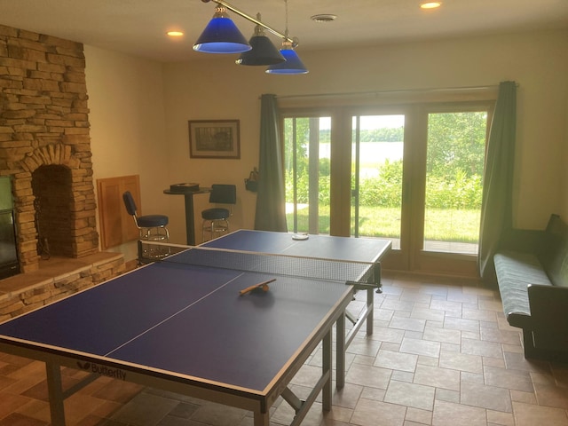 recreation room featuring a stone fireplace, visible vents, and recessed lighting