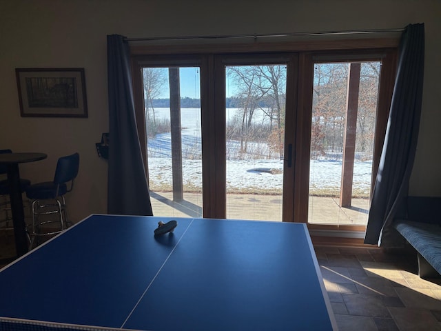 recreation room featuring stone finish flooring and a water view