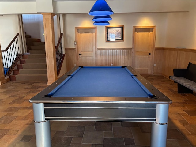 recreation room with wooden walls, a wainscoted wall, pool table, stone finish flooring, and decorative columns