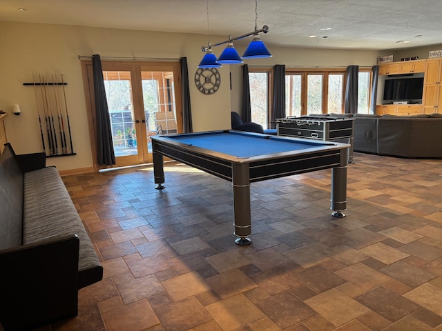 rec room featuring french doors, stone finish floor, a wealth of natural light, and baseboards