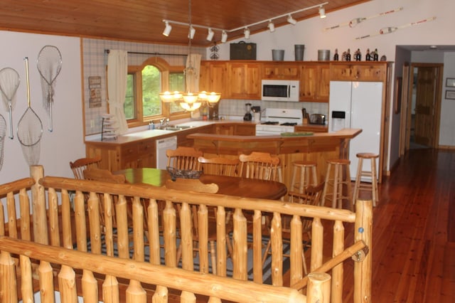 kitchen with white appliances, tasteful backsplash, hardwood / wood-style flooring, light countertops, and a sink