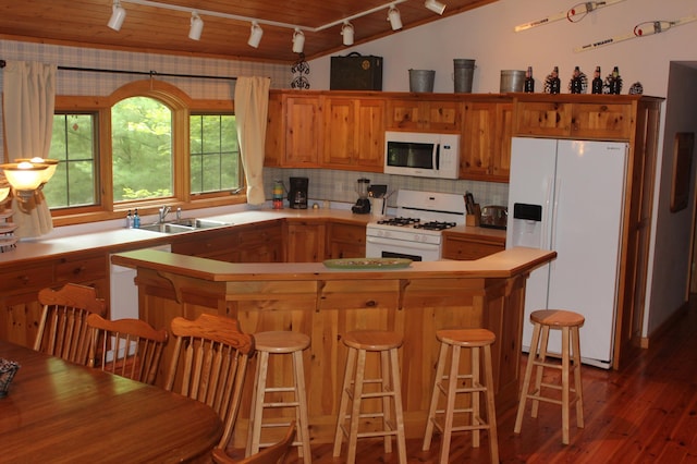 kitchen with tasteful backsplash, light countertops, a sink, wood finished floors, and white appliances