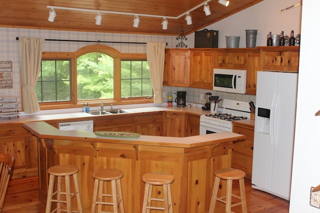 kitchen featuring white appliances, a sink, light countertops, light wood finished floors, and tasteful backsplash