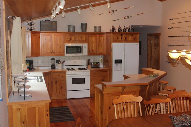 kitchen with vaulted ceiling, light countertops, white appliances, and backsplash