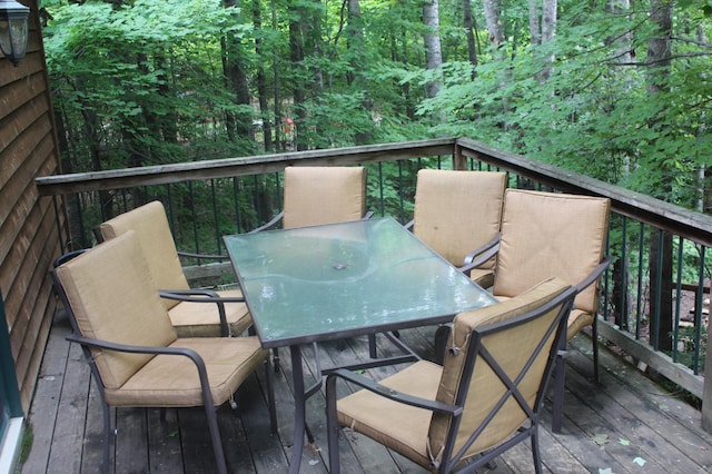 wooden terrace with outdoor dining area and a wooded view