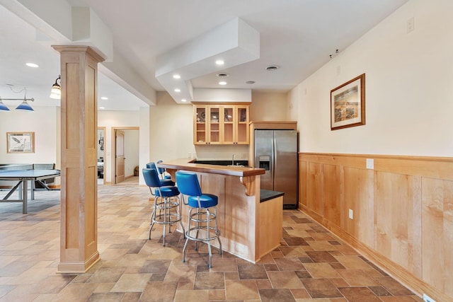 7251 County Rd B, Siren Twp, WI 54872 - kitchen with stone finish flooring, stainless steel refrigerator with ice dispenser, a kitchen breakfast bar, and decorative columns