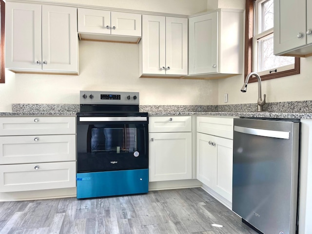 kitchen featuring light stone counters, range with electric stovetop, light wood-style flooring, and dishwasher