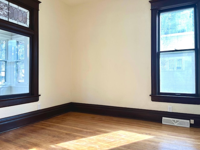 spare room featuring baseboards, visible vents, and wood finished floors