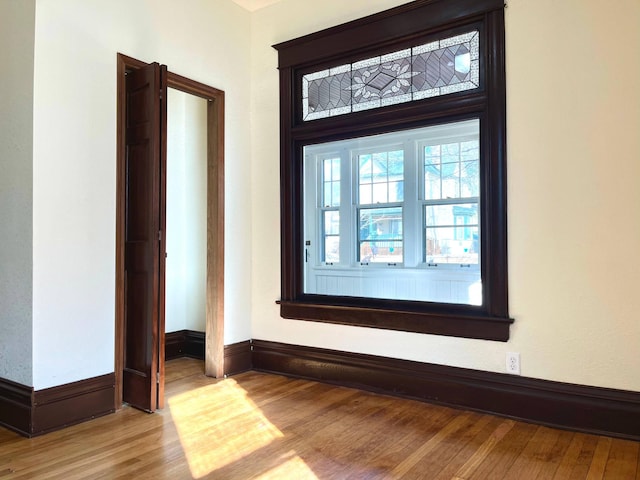 spare room with baseboards and wood finished floors