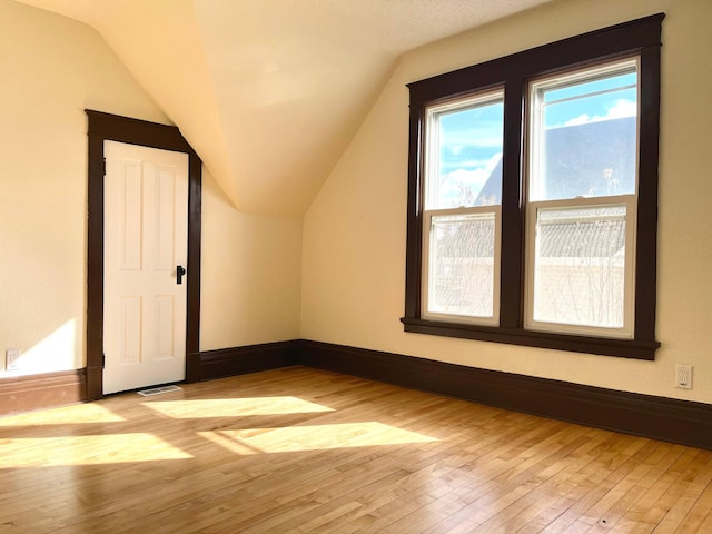 bonus room featuring hardwood / wood-style flooring, visible vents, baseboards, and vaulted ceiling