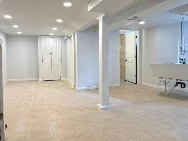 finished below grade area featuring baseboards, light tile patterned floors, visible vents, and recessed lighting