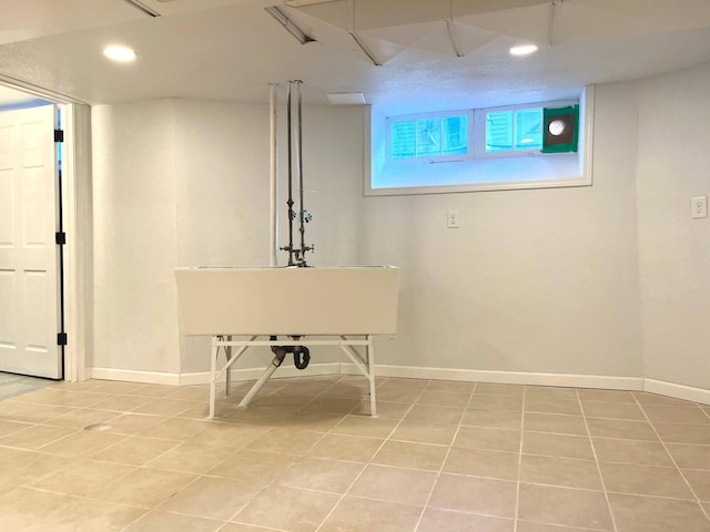 basement featuring light tile patterned flooring and baseboards