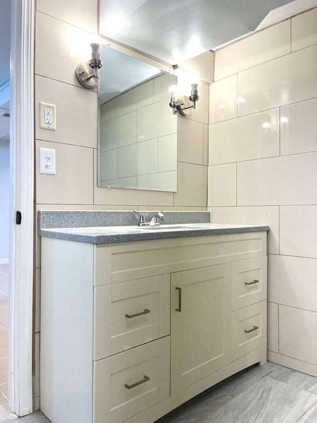 bathroom with tile walls, marble finish floor, and vanity