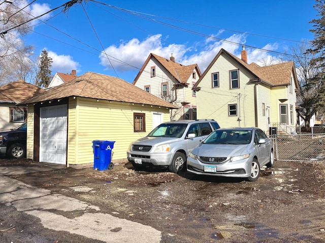 view of home's exterior with a garage, fence, an outdoor structure, and roof with shingles