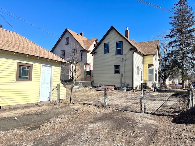 rear view of house featuring a shingled roof, a gate, and fence