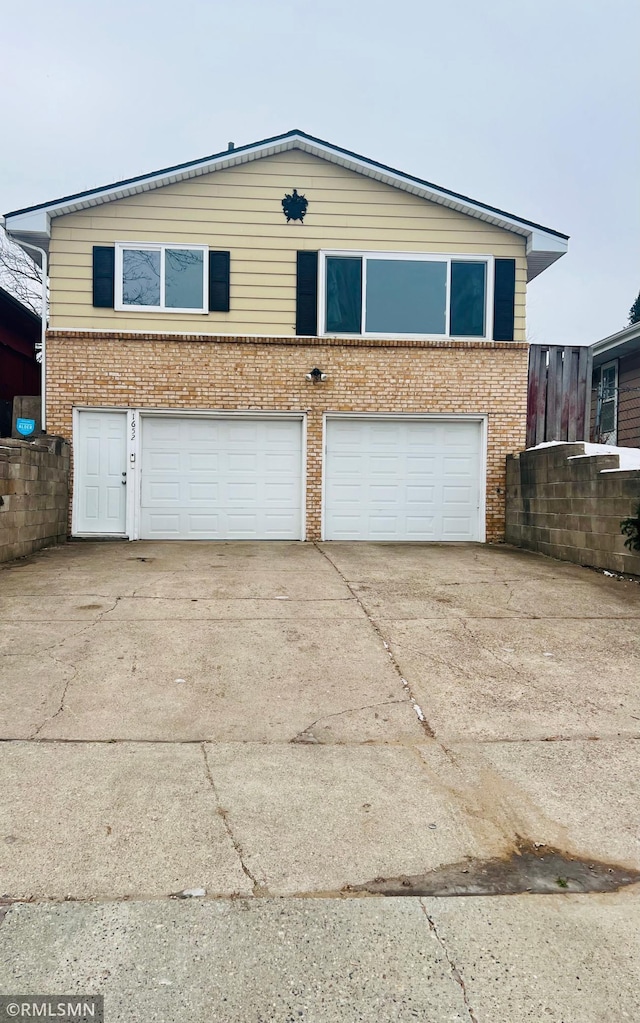 exterior space featuring concrete driveway, brick siding, and an attached garage