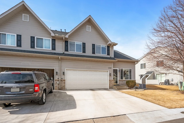 view of front facade with central air condition unit, an attached garage, and driveway