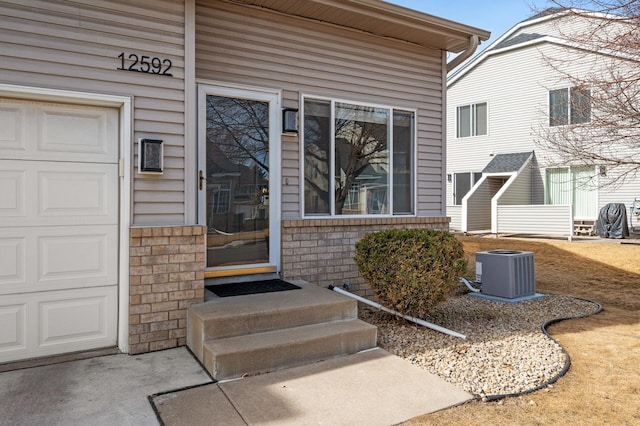 view of exterior entry featuring central air condition unit and an attached garage