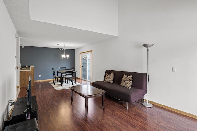 living area featuring an inviting chandelier, a textured ceiling, baseboards, and wood finished floors