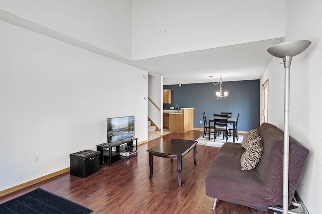 living area featuring a chandelier, baseboards, wood finished floors, and stairs