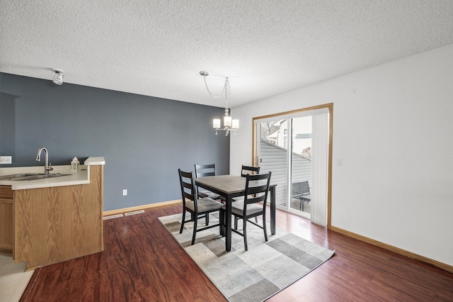 dining space with an inviting chandelier, wood finished floors, baseboards, and a textured ceiling