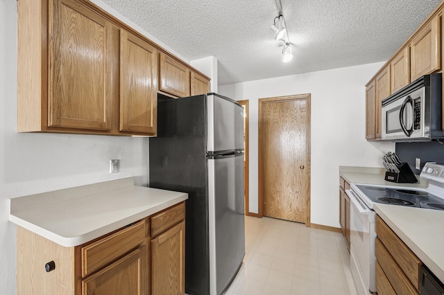 kitchen featuring a textured ceiling, stainless steel appliances, brown cabinetry, light countertops, and light floors