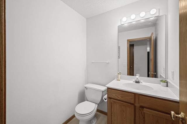 half bath featuring baseboards, a textured ceiling, vanity, and toilet