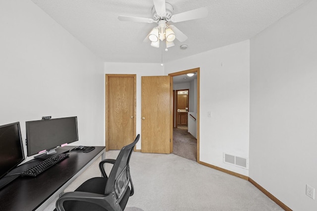 home office with visible vents, baseboards, ceiling fan, light colored carpet, and a textured ceiling