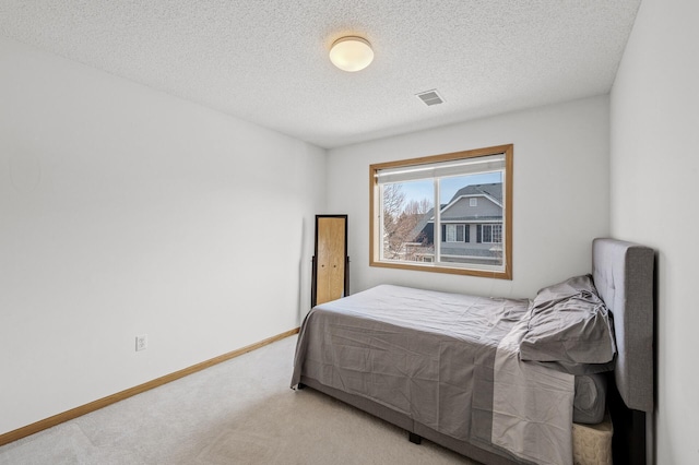 carpeted bedroom with visible vents, baseboards, and a textured ceiling