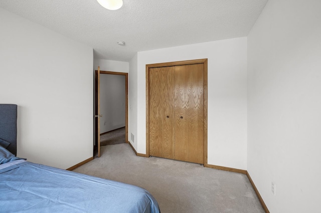 carpeted bedroom featuring a closet, visible vents, a textured ceiling, and baseboards