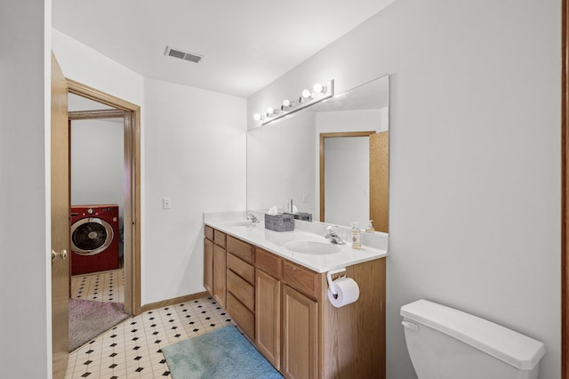 bathroom featuring visible vents, washer / clothes dryer, a sink, tile patterned floors, and toilet