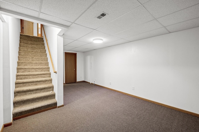 finished below grade area featuring a drop ceiling, visible vents, carpet flooring, and stairway