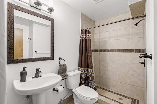 full bathroom with toilet, visible vents, a tile shower, and a sink