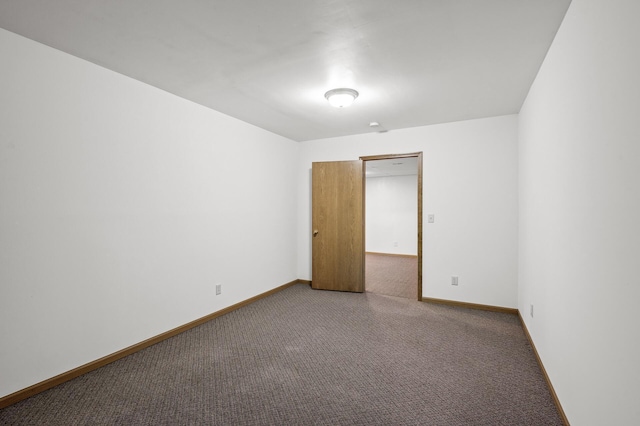 spare room featuring carpet and baseboards