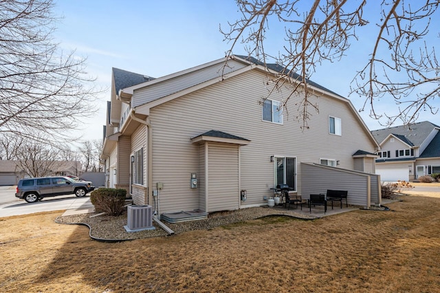 rear view of house featuring a yard, a patio, cooling unit, and a shingled roof