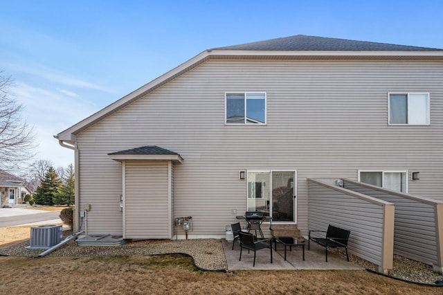 back of property with a patio area, a shingled roof, and central AC