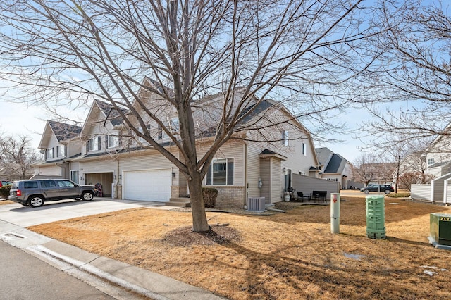 view of front of house with central AC unit, an attached garage, a residential view, concrete driveway, and brick siding