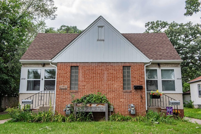 back of house with roof with shingles and brick siding