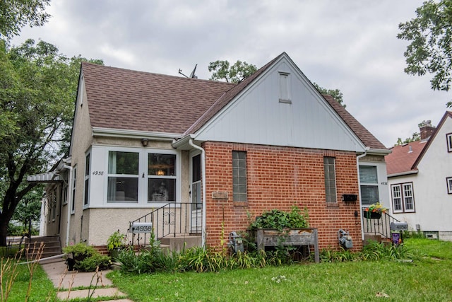 bungalow with a shingled roof, a front lawn, and brick siding