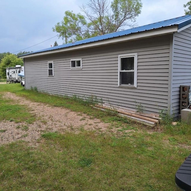 view of side of home with metal roof and a lawn