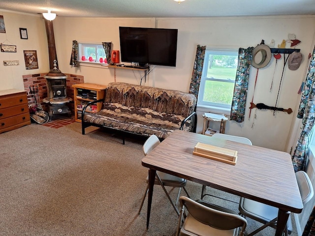 living area with a textured ceiling, carpet floors, ornamental molding, and a wood stove