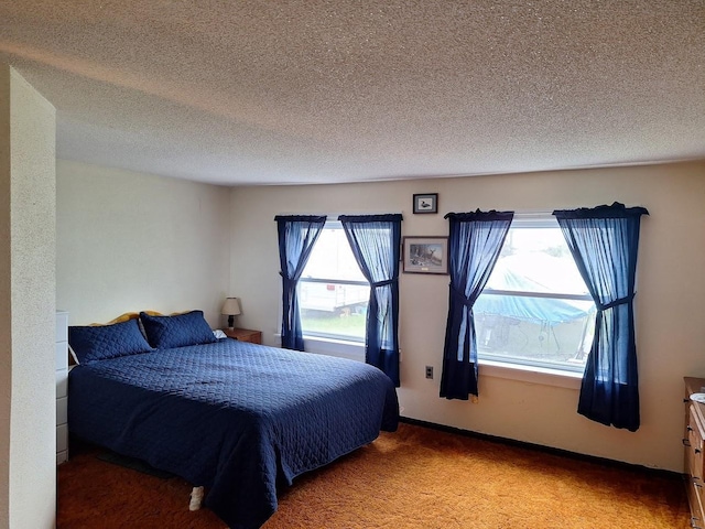 bedroom with light carpet, multiple windows, and a textured ceiling